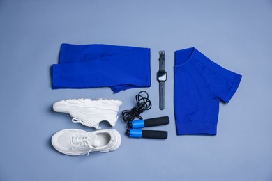Photo of Sportswear, sneakers, skipping rope and wrist watch on grey background, flat lay