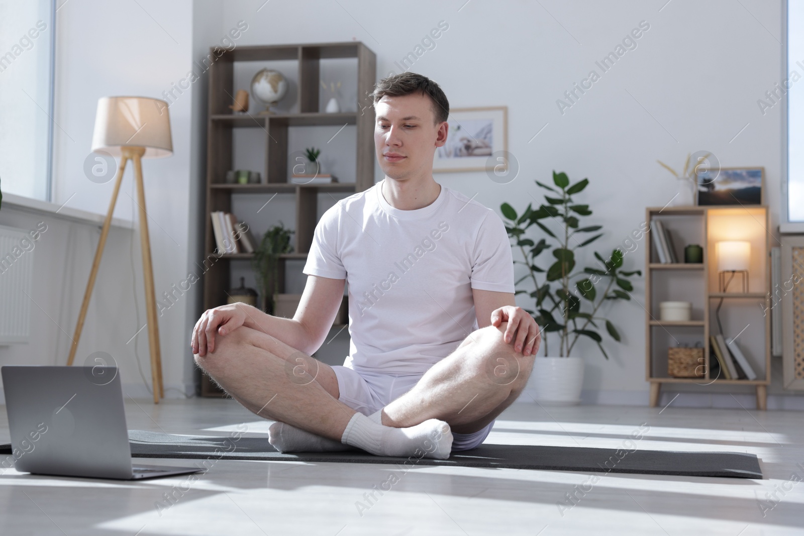 Man having online yoga class via laptop at home Photo of Man having online yoga class via laptop at home