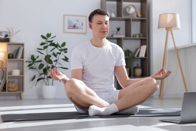 Photo of Man having online yoga class via laptop at home