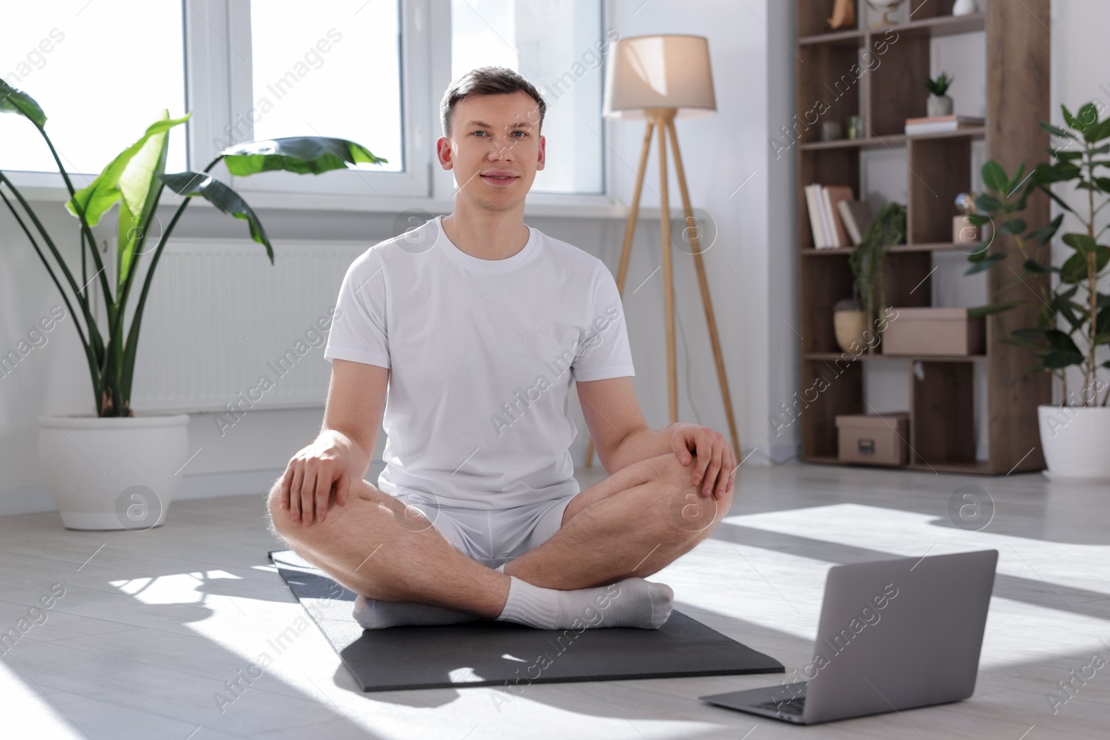 Man having online yoga class via laptop at home Photo of Man having online yoga class via laptop at home