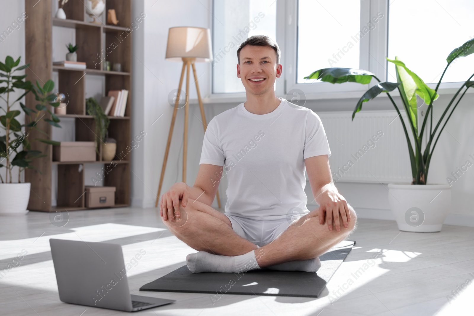 Man having online yoga class via laptop at home Photo of Man having online yoga class via laptop at home