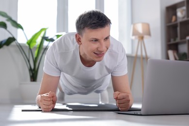 Photo of Man having online yoga class via laptop at home