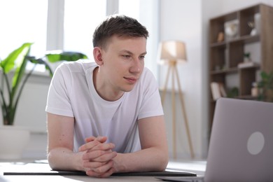 Photo of Man having online yoga class via laptop at home
