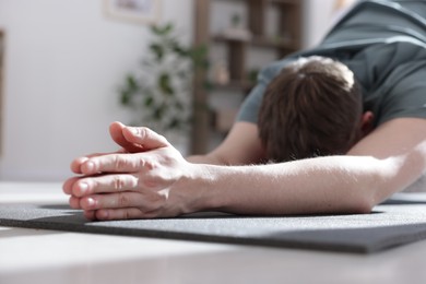 Photo of Young man practicing yoga at home, closeup