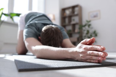 Photo of Young man practicing yoga at home, closeup