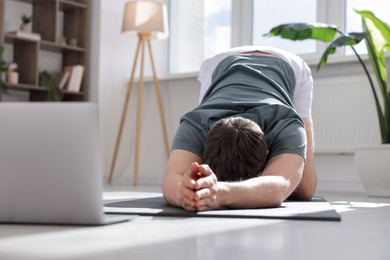 Photo of Man having online yoga class via laptop at home