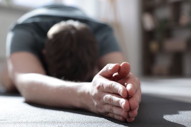 Photo of Young man practicing yoga at home, closeup