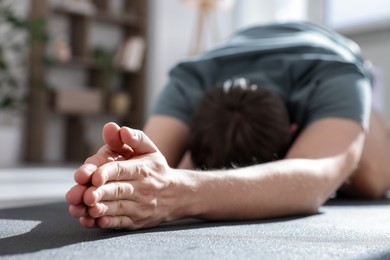 Photo of Young man practicing yoga at home, closeup