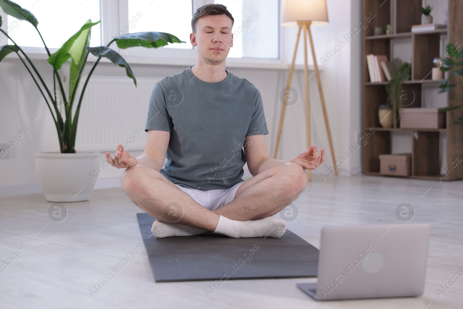 Man having online yoga class via laptop at home Photo of Man having online yoga class via laptop at home