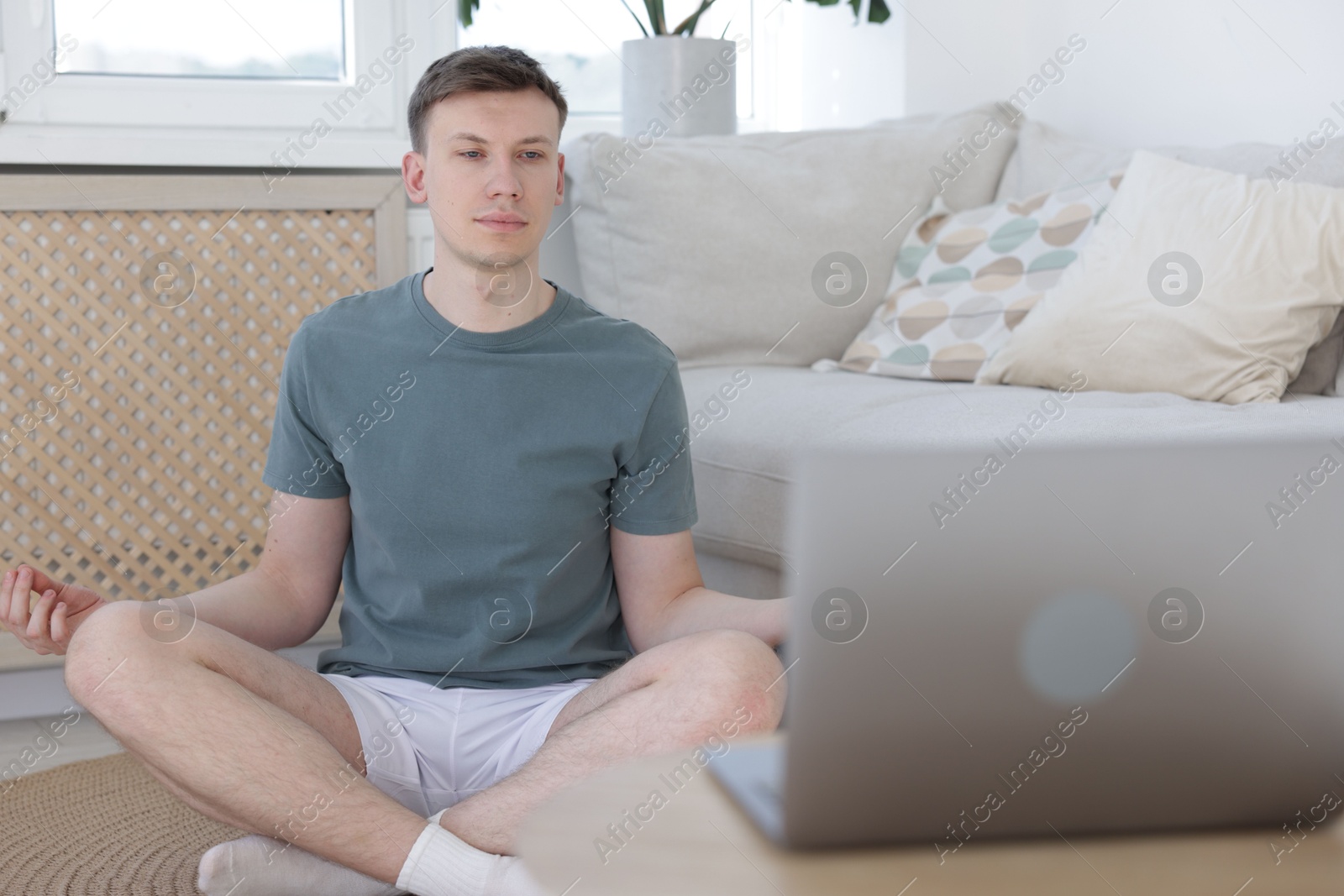 Man having online yoga class via laptop at home Photo of Man having online yoga class via laptop at home