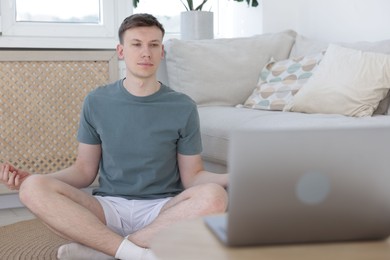 Photo of Man having online yoga class via laptop at home