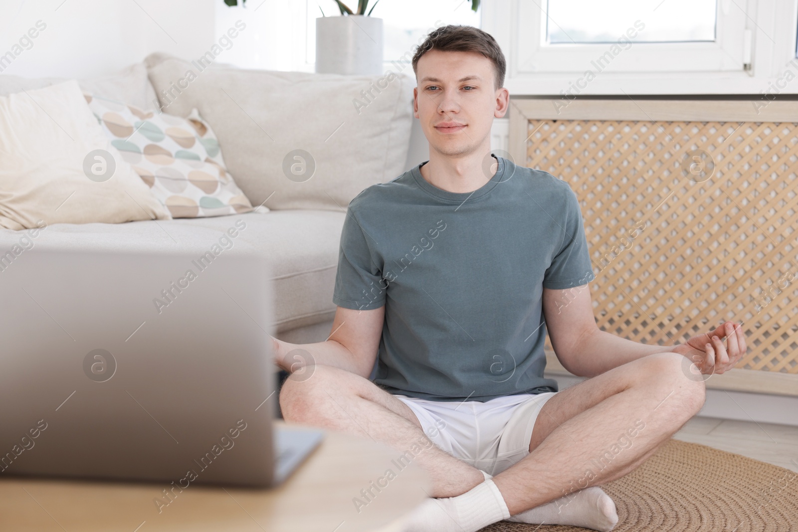 Man having online yoga class via laptop at home Photo of Man having online yoga class via laptop at home
