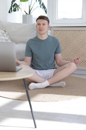 Photo of Man having online yoga class via laptop at home