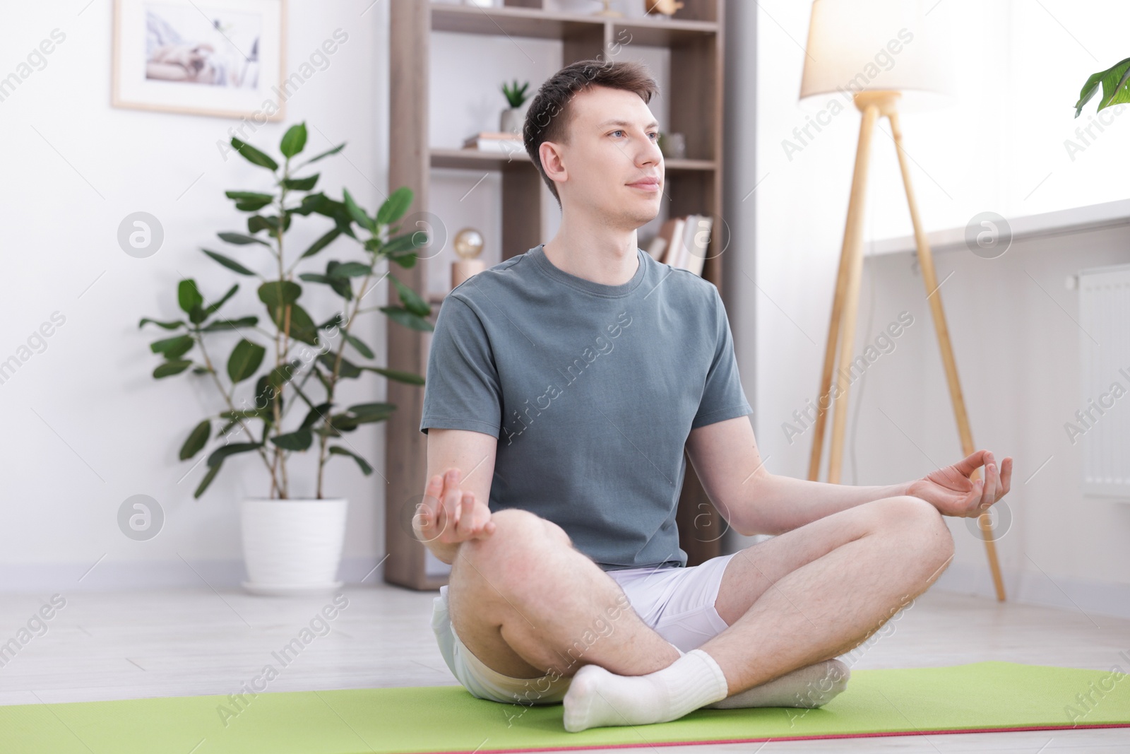 Young man practicing yoga on mat at home Photo of Young man practicing yoga on mat at home