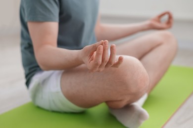 Photo of Young man practicing yoga at home, closeup