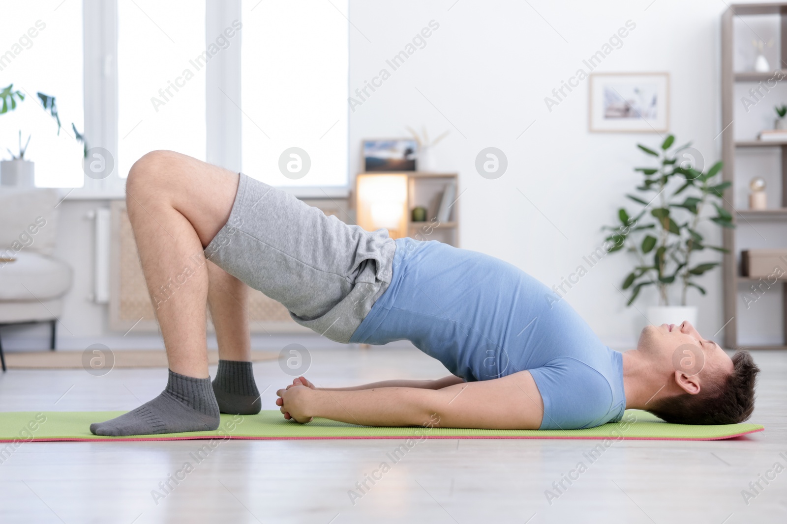 Young man practicing yoga on mat at home Photo of Young man practicing yoga on mat at home