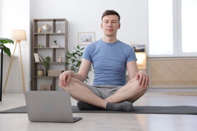 Photo of Man having online yoga class via laptop at home