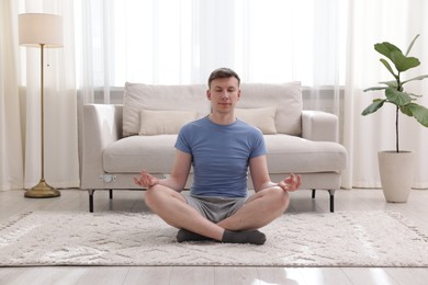Photo of Young man practicing yoga on floor at home