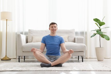 Photo of Young man practicing yoga on floor at home