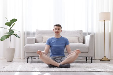 Photo of Young man practicing yoga on floor at home
