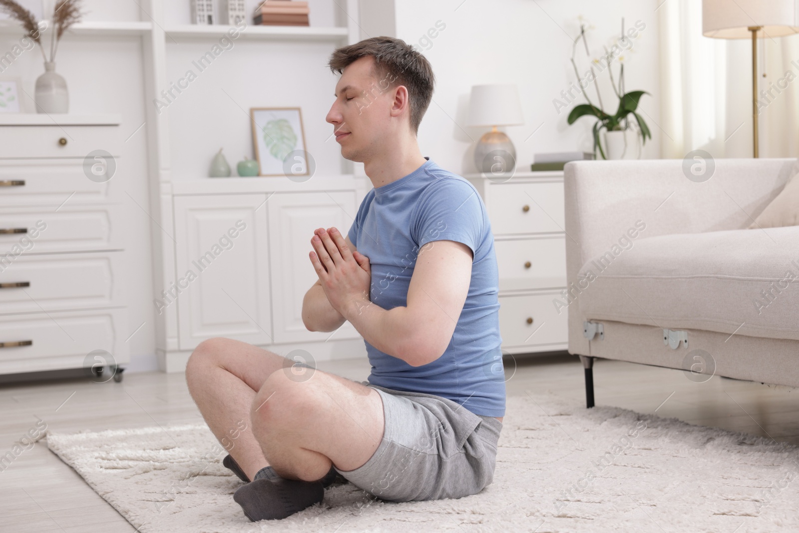 Young man practicing yoga on floor at home Photo of Young man practicing yoga on floor at home
