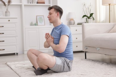 Photo of Young man practicing yoga on floor at home