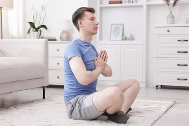 Photo of Young man practicing yoga on floor at home