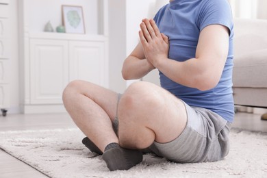 Photo of Young man practicing yoga at home, closeup