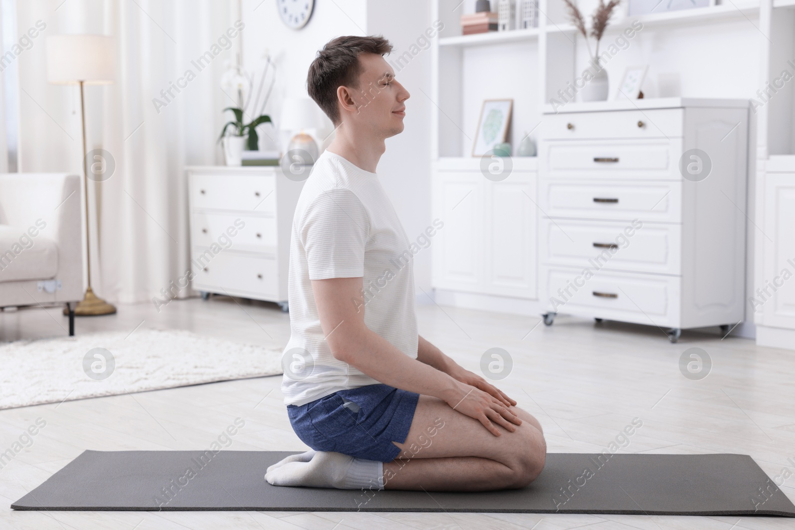 Young man practicing yoga on mat at home Photo of Young man practicing yoga on mat at home
