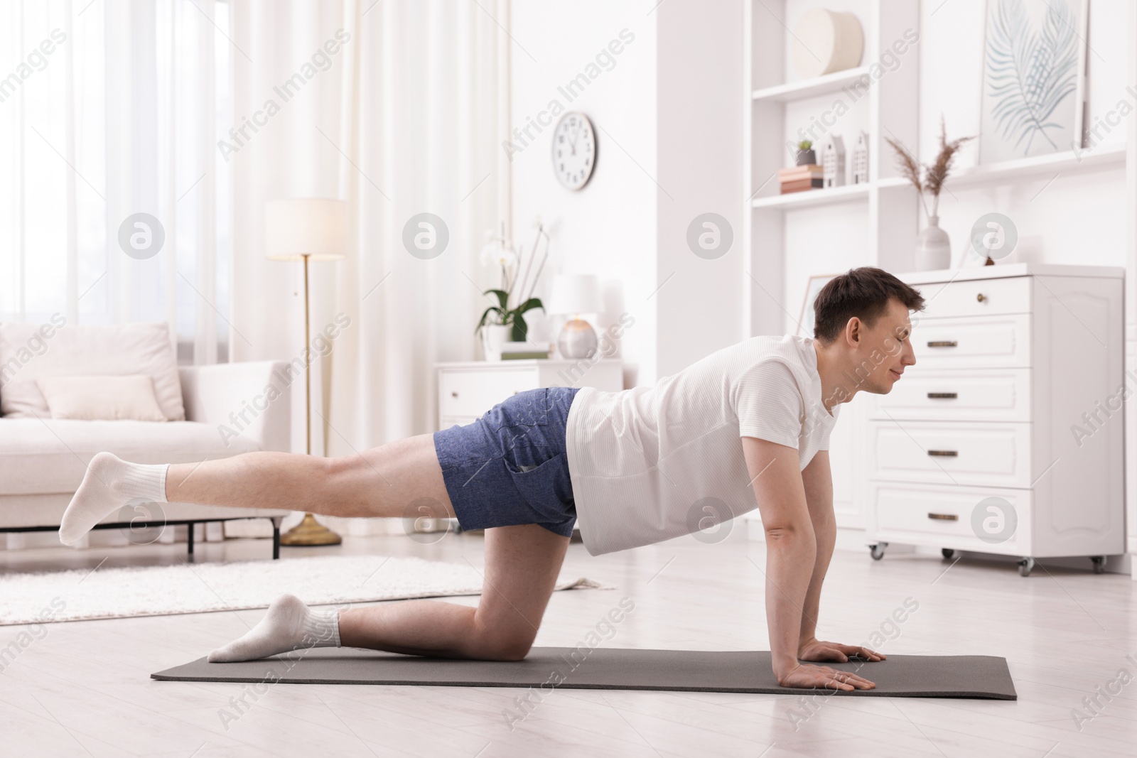 Young man practicing yoga on mat at home. Space for text Photo of Young man practicing yoga on mat at home. Space for text