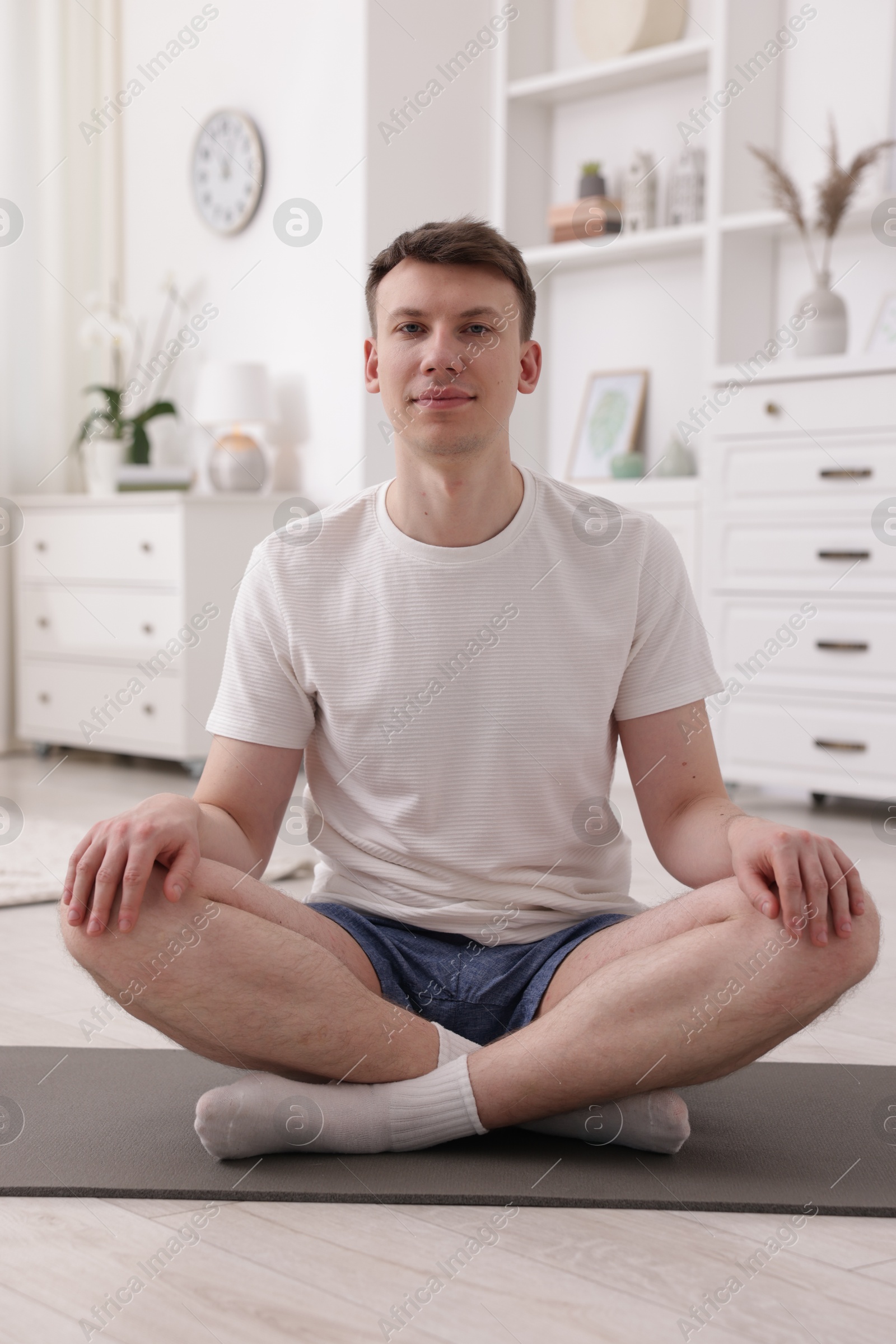 Young man practicing yoga on mat at home Photo of Young man practicing yoga on mat at home