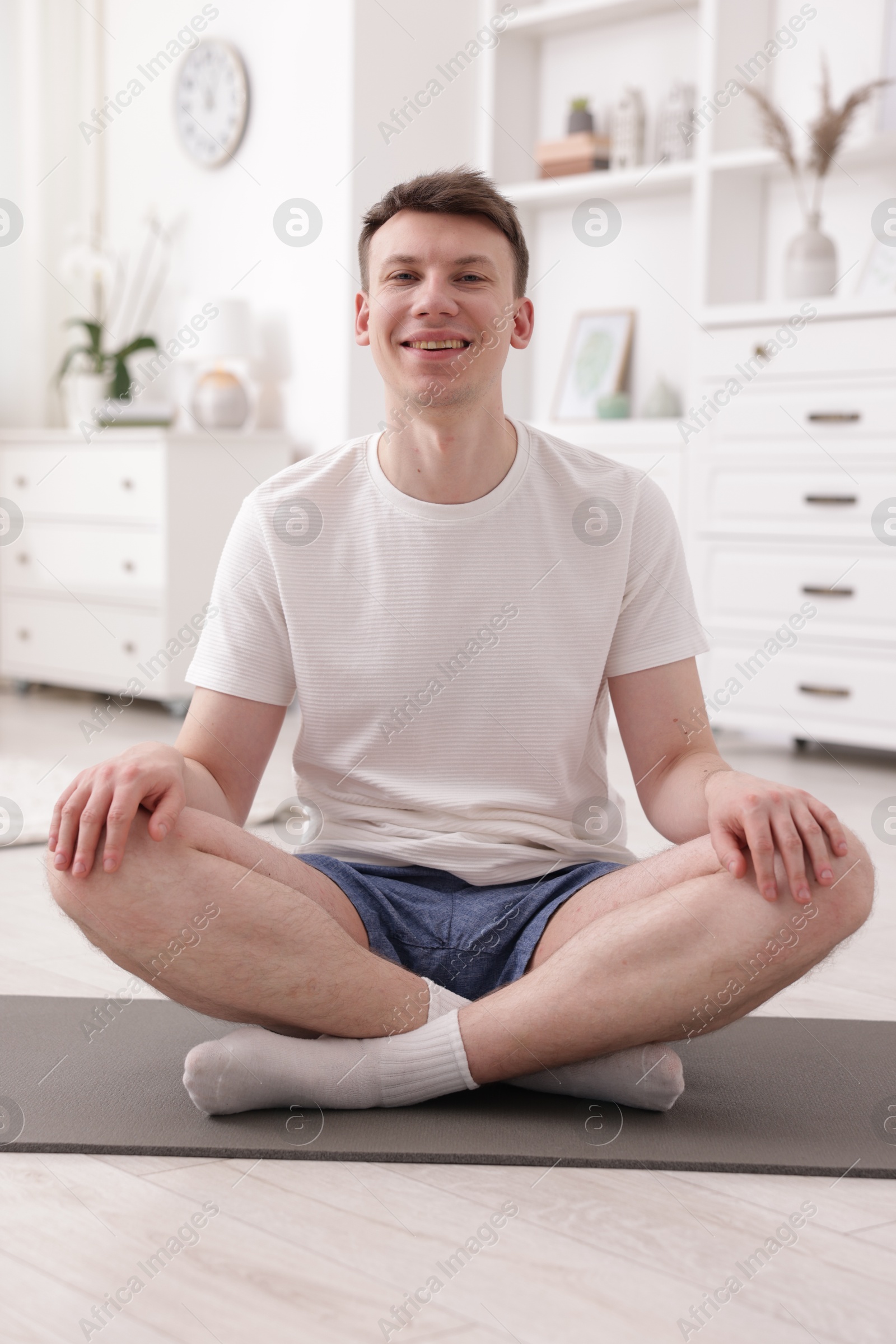 Young man practicing yoga on mat at home Photo of Young man practicing yoga on mat at home
