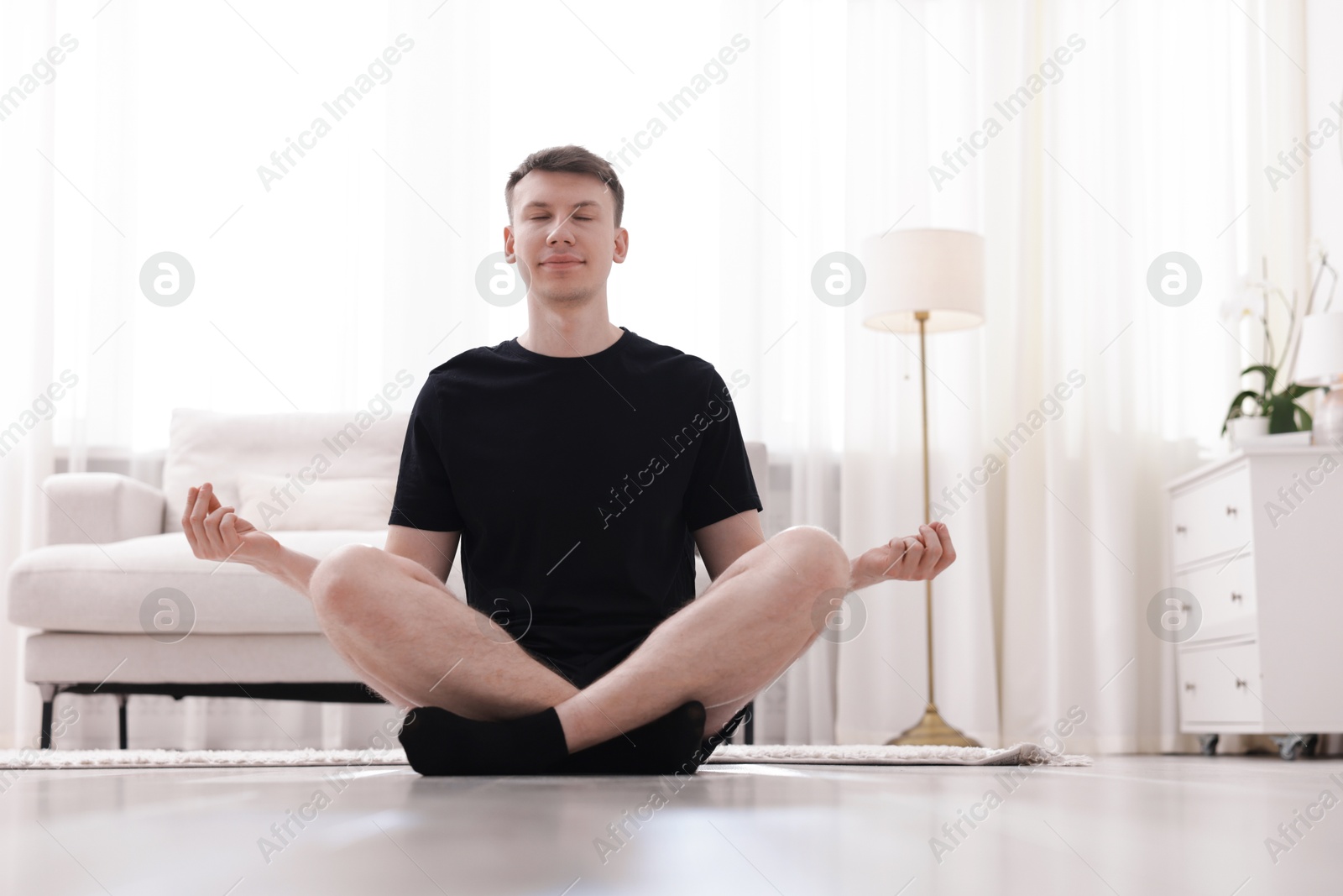 Young man practicing yoga on mat at home Photo of Young man practicing yoga on mat at home