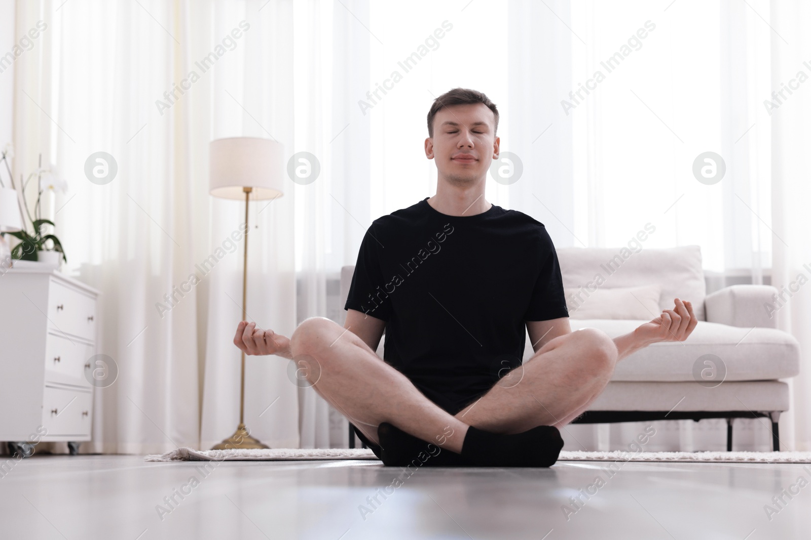 Young man practicing yoga on mat at home. Space for text Photo of Young man practicing yoga on mat at home. Space for text