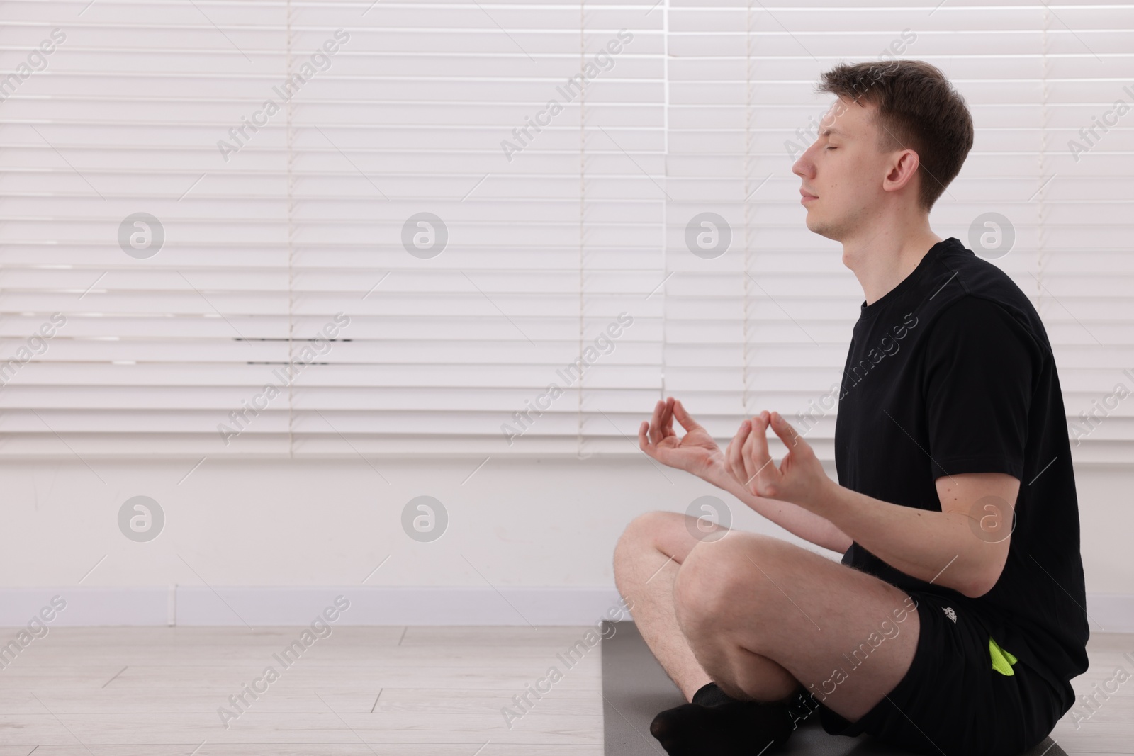 Young man practicing yoga on mat at home. Space for text Photo of Young man practicing yoga on mat at home. Space for text