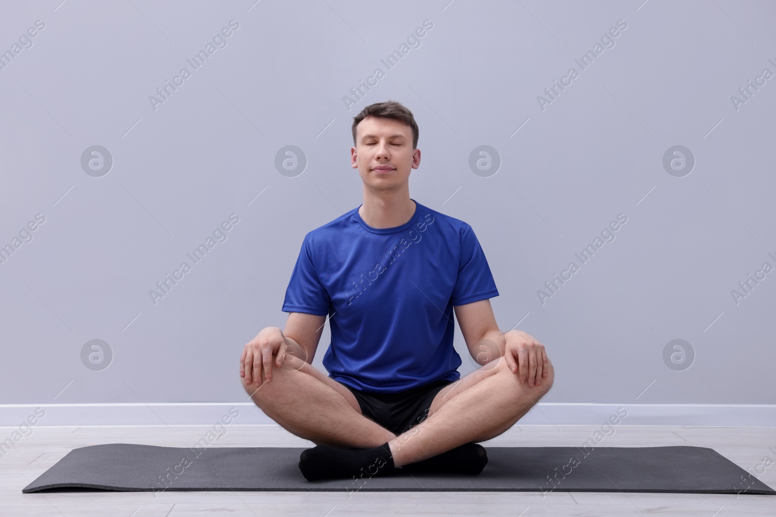 Young man practicing yoga on mat indoors Photo of Young man practicing yoga on mat indoors