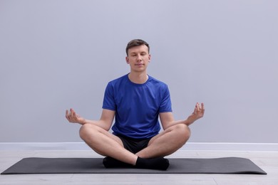Photo of Young man practicing yoga on mat indoors