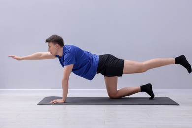 Photo of Young man practicing yoga on mat indoors