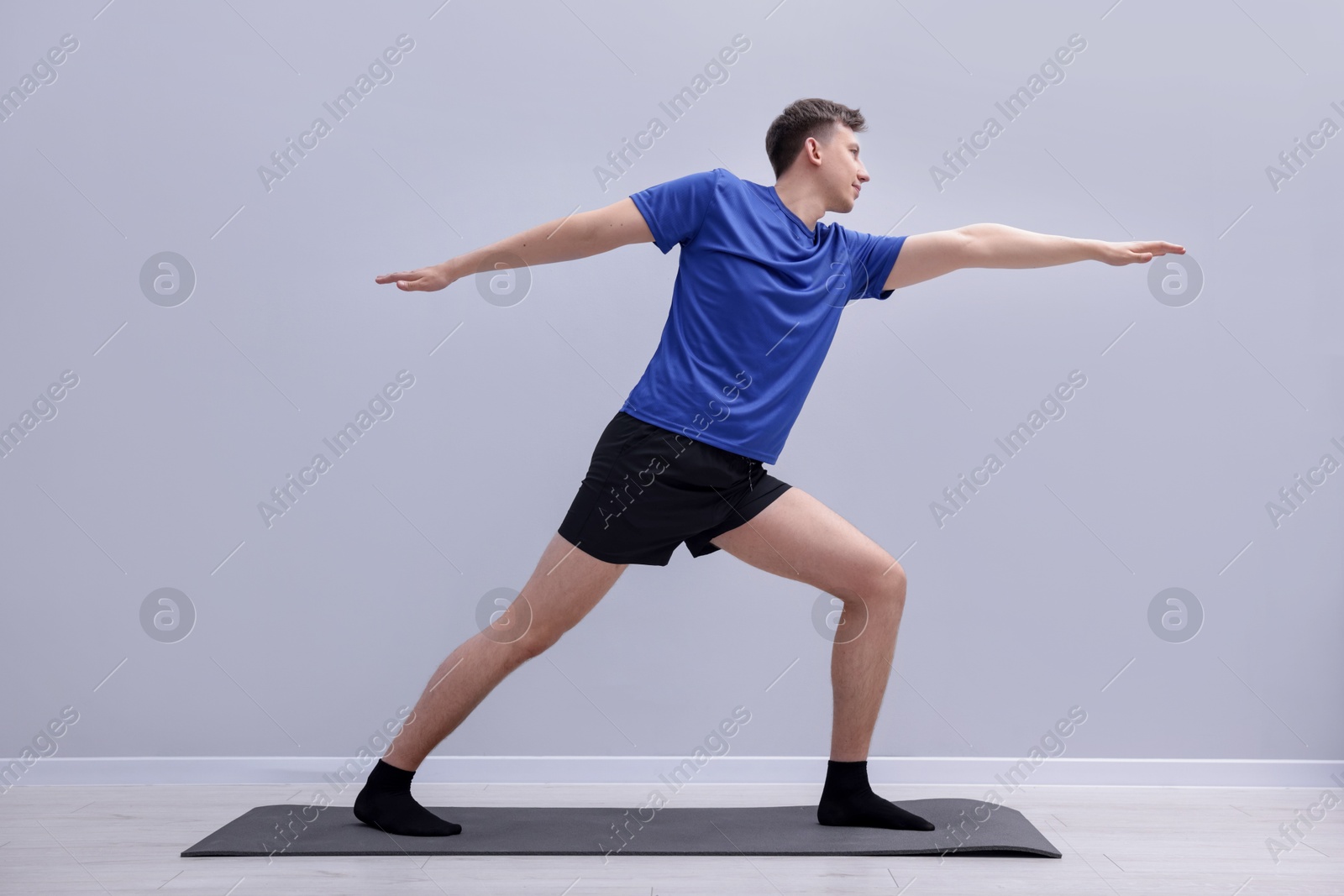 Young man practicing yoga on mat indoors Photo of Young man practicing yoga on mat indoors