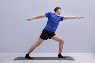 Photo of Young man practicing yoga on mat indoors