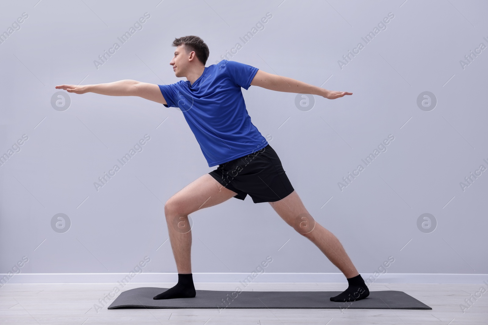Young man practicing yoga on mat indoors Photo of Young man practicing yoga on mat indoors