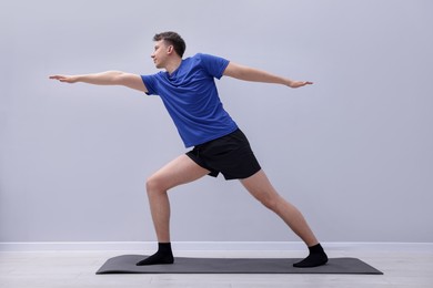 Photo of Young man practicing yoga on mat indoors