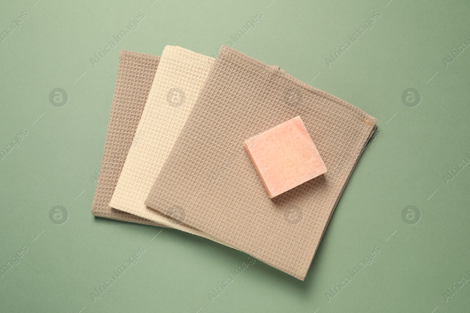 Clean waffle towels and soap bar on green background, top view Photo of Clean waffle towels and soap bar on green background, top view