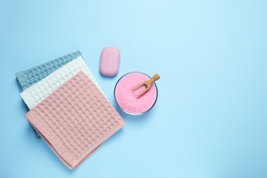 Photo of Clean waffle towels and cosmetic products on light blue background, flat lay. Space for text