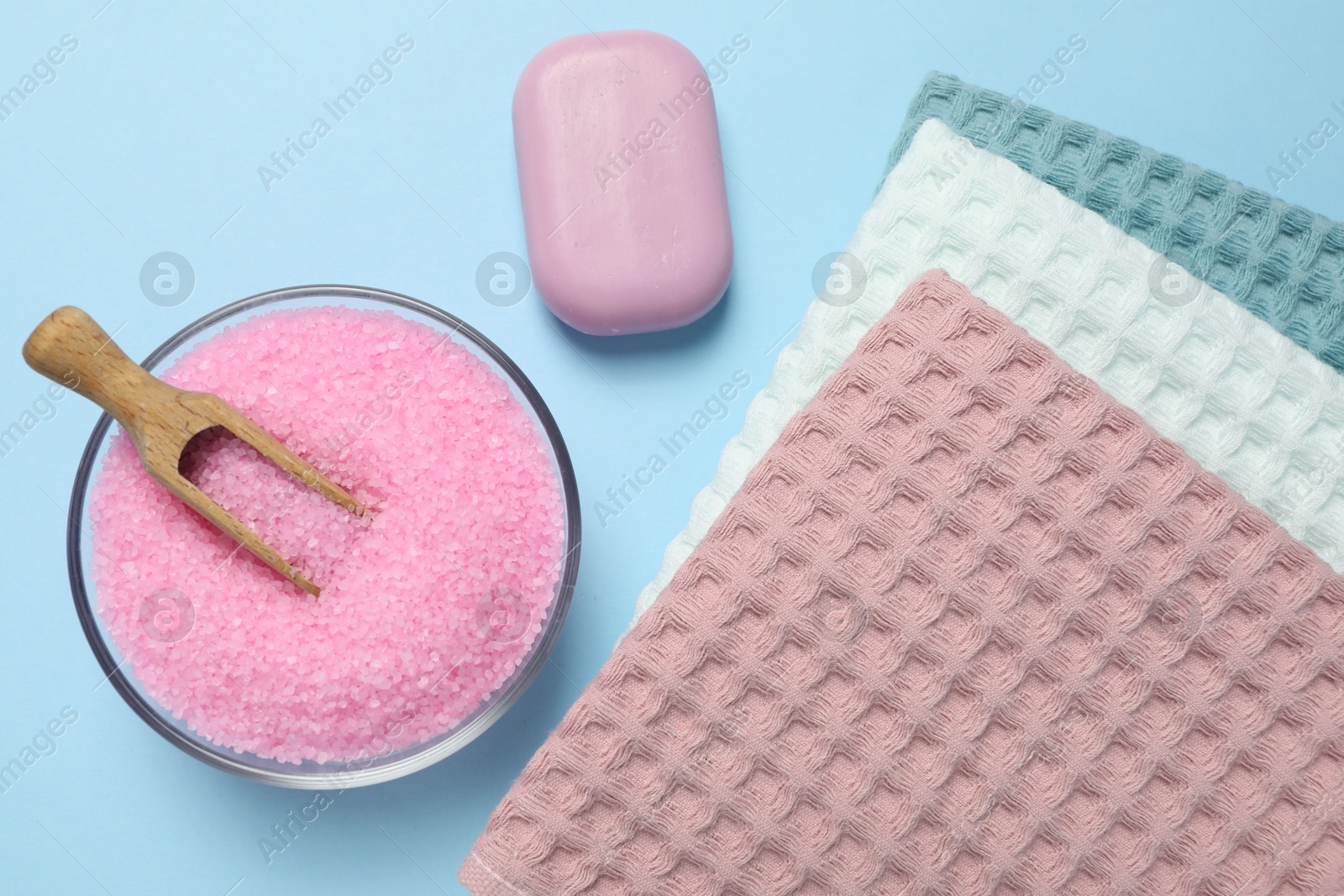 Clean waffle towels and cosmetic products on light blue background, flat lay Photo of Clean waffle towels and cosmetic products on light blue background, flat lay