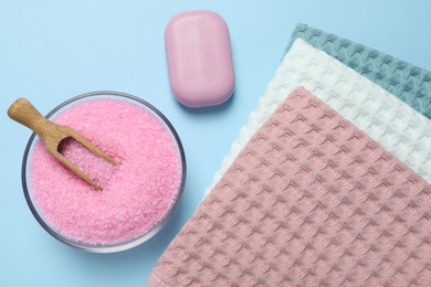Photo of Clean waffle towels and cosmetic products on light blue background, flat lay