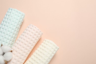 Photo of Clean waffle towels and cotton flower on beige background, flat lay. Space for text