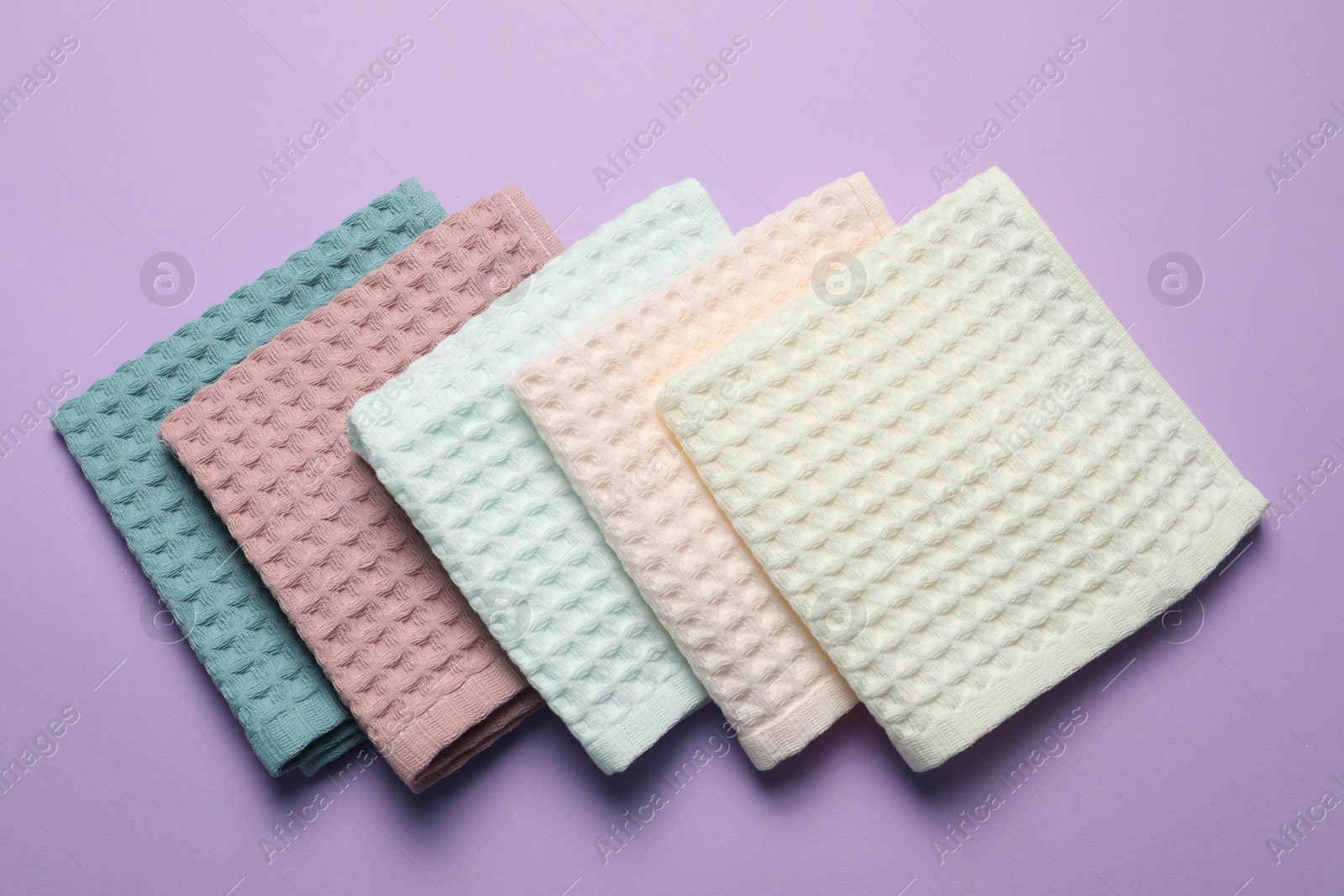 Clean waffle towels on violet background, flat lay Photo of Clean waffle towels on violet background, flat lay