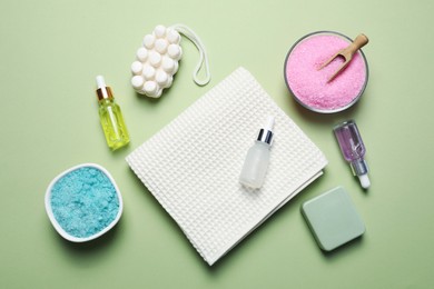 Photo of Clean waffle towel and cosmetic products on light green background, flat lay