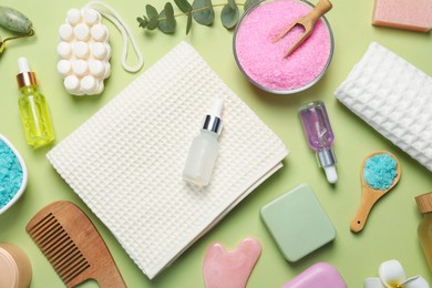 Photo of Clean waffle towels and cosmetic products on light green background, flat lay